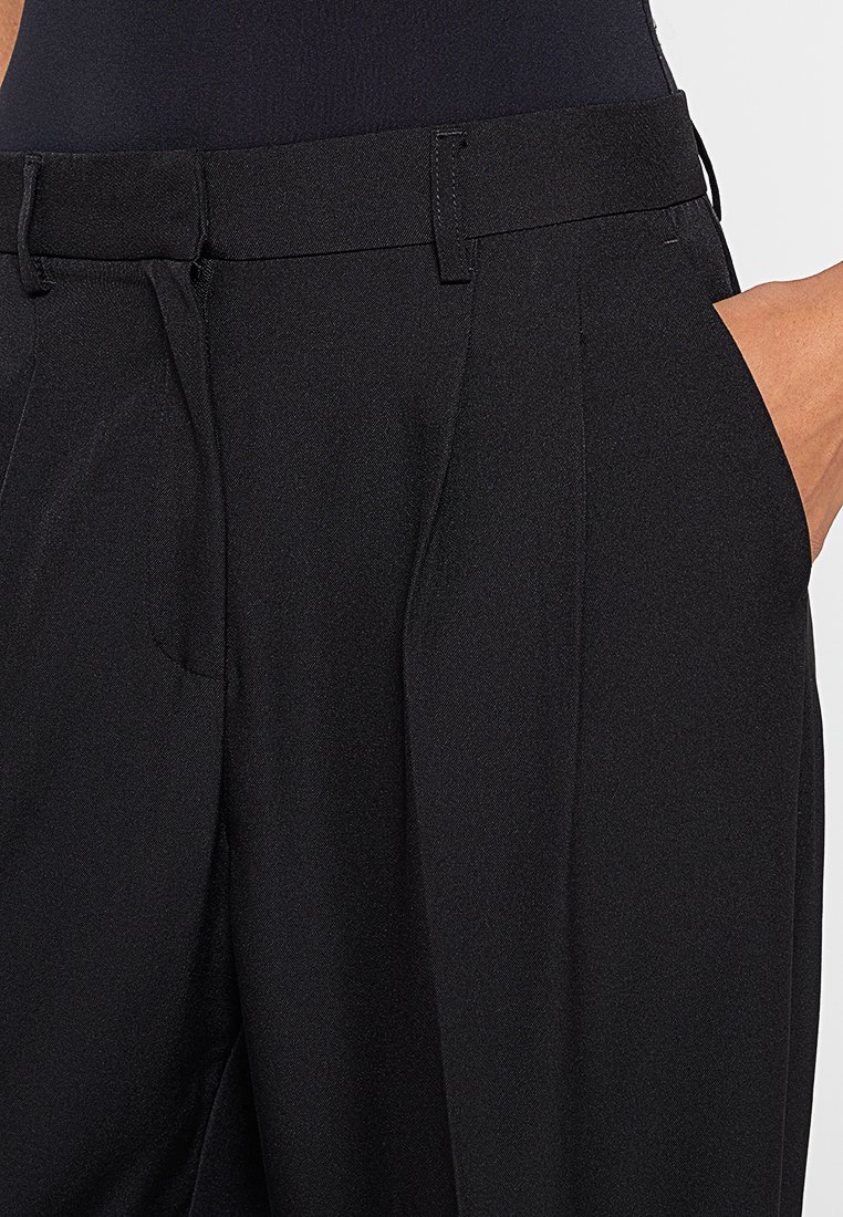 Pantaloni neri su misura con gambe diritte, caratterizzati da una texture liscia, pince frontali e una leggera lucentezza. Comprendono tasche laterali e passanti per cintura.