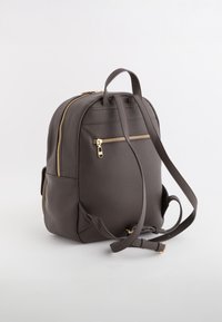 Grau strukturierter Rucksack mit goldenen Reißverschlüssen, verstellbaren Trägern und einer vorderen Reißverschlusstasche. Verfügt über eine runde Form und Seitentaschen.