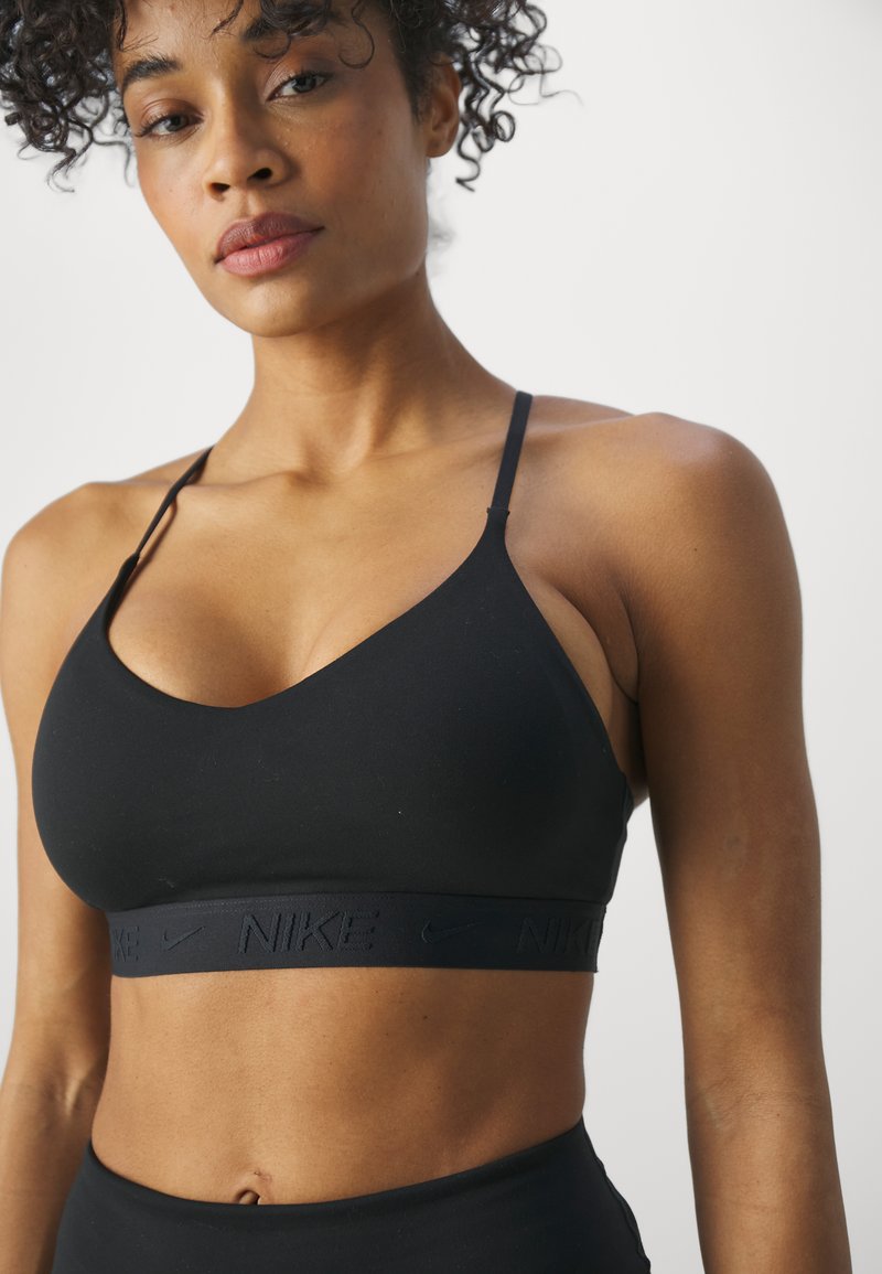 Zwarte sportbeha met dunne banden, zachte stof en elastische band met reliëf Nike-logo. Eenvoudig ontwerp, zonder patronen of accenten.