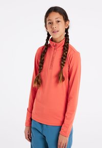 Koraalkleurig sporttop met lange mouwen, een halve ritssluiting en logo-detail. Glad textuur, getailleerde pasvorm, gecombineerd met blauwe broek.