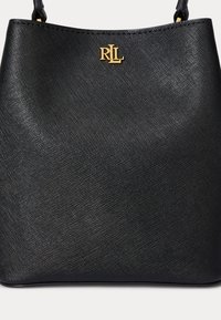 Sort tekstureret læderhåndtaske med gyldent RLL-logo og sorte håndtag mod en hvid baggrund.