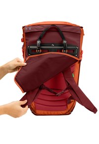 Mochila con un exterior naranja y un interior burdeos. Cuenta con correas ajustables, un bolsillo con cremallera y soporte trasero acolchado.