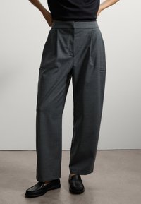 Pantaloni a quadri grigi con vestibilità sartoriale, dotati di pieghe, tasche laterali e un design a gamba dritta, abbinati a mocassini neri.