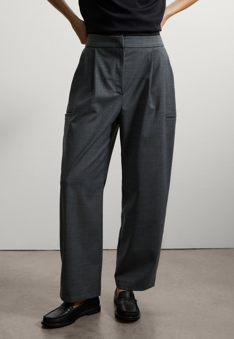Pantaloni a quadri grigi con vestibilità sartoriale, dotati di pieghe, tasche laterali e un design a gamba dritta, abbinati a mocassini neri.