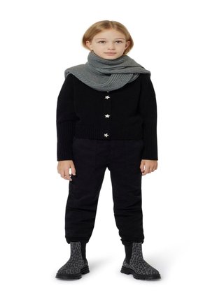 Cardigan noir en tricot avec des boutons en forme d'étoile, associé à un pantalon noir et une écharpe en tricot grise. Les bottes affichent un design imprimé léopard.