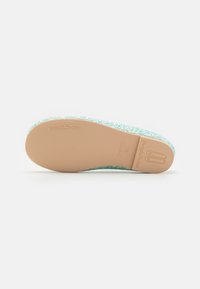 Semelle de ballerine en brun clair avec un revêtement en paillettes bleu menthe texturé. Présente un logo en relief sur le talon et un dessous lisse.