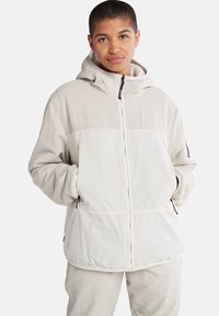 Leichte, kapuzenjacke in Beige und Weiß. Verfügt über einen Reißverschluss, Seitentaschen und elastische Bündchen. Weiche Textur mit einem gemütlichen Innenfutter.