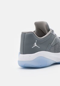 Szare skórzane sneakersy z siateczkowymi detalami, białym logo Jumpman i niebieską przezroczystą podeszwą. Posiadają wyściełany kołnierz dla wygody.