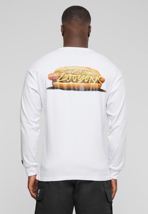 White long-sleeve t-shirt featuring a graphic of a hot dog with yellow mustard and sauerkraut, text "ZOYORK" in yellow.