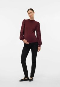 Burgundy topp med ribsade puffärmar, kombinerad med svarta slim-fit byxor och svarta ballerinas. Slät textur med figurnära siluett.