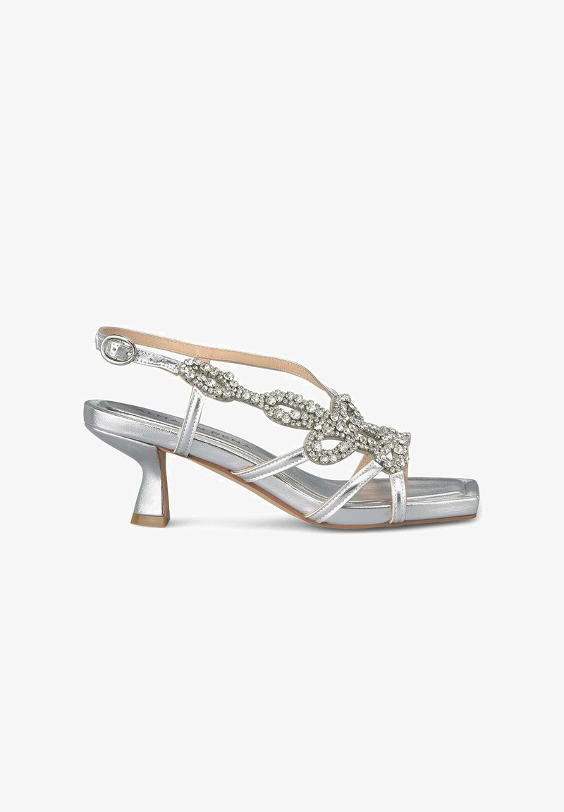 Zilveren slingback sandaal met een lage blokhak. Voorzien van een decoratieve beaded band met een knoopontwerp. Glad metallic afwerking.