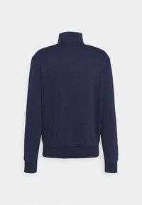 Dunkelblaues Pullover-Sweatshirt mit hohem Kragen, langen Ärmeln und gerippten Bündchen; aus glattem Stoff gefertigt und mit einem lockeren Schnitt.