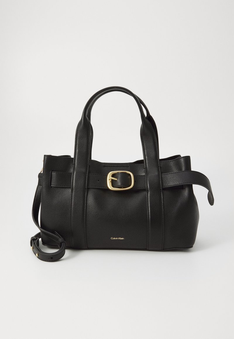 Sac à main en cuir noir avec double poignée, détail boucle dorée sur le devant, bandoulière amovible et petit logo Calvin Klein.