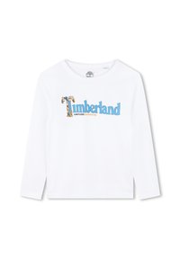 Camiseta de manga larga blanca con el texto "Timberland" en azul y naranja, con un gráfico de un árbol que acentúa el diseño. Material de algodón suave.