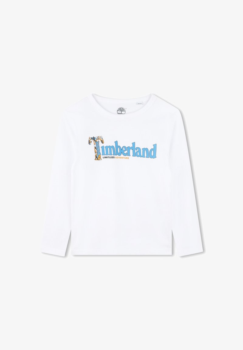 Camiseta de manga larga blanca con el texto "Timberland" en azul y naranja, con un gráfico de un árbol que acentúa el diseño. Material de algodón suave.