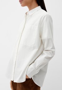 Witte langetermijnshirt met een puntige kraag, enkele borstzak en knoopmanschetten. Zachte stof met een gladde textuur en een ontspannen pasvorm.