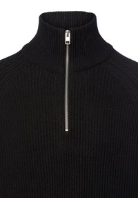 Sort, ribbet turtleneck sweater med en halvmåde lynlås ved halsen. Materialet ser strikket ud, hvilket giver en tekstureret overflade.