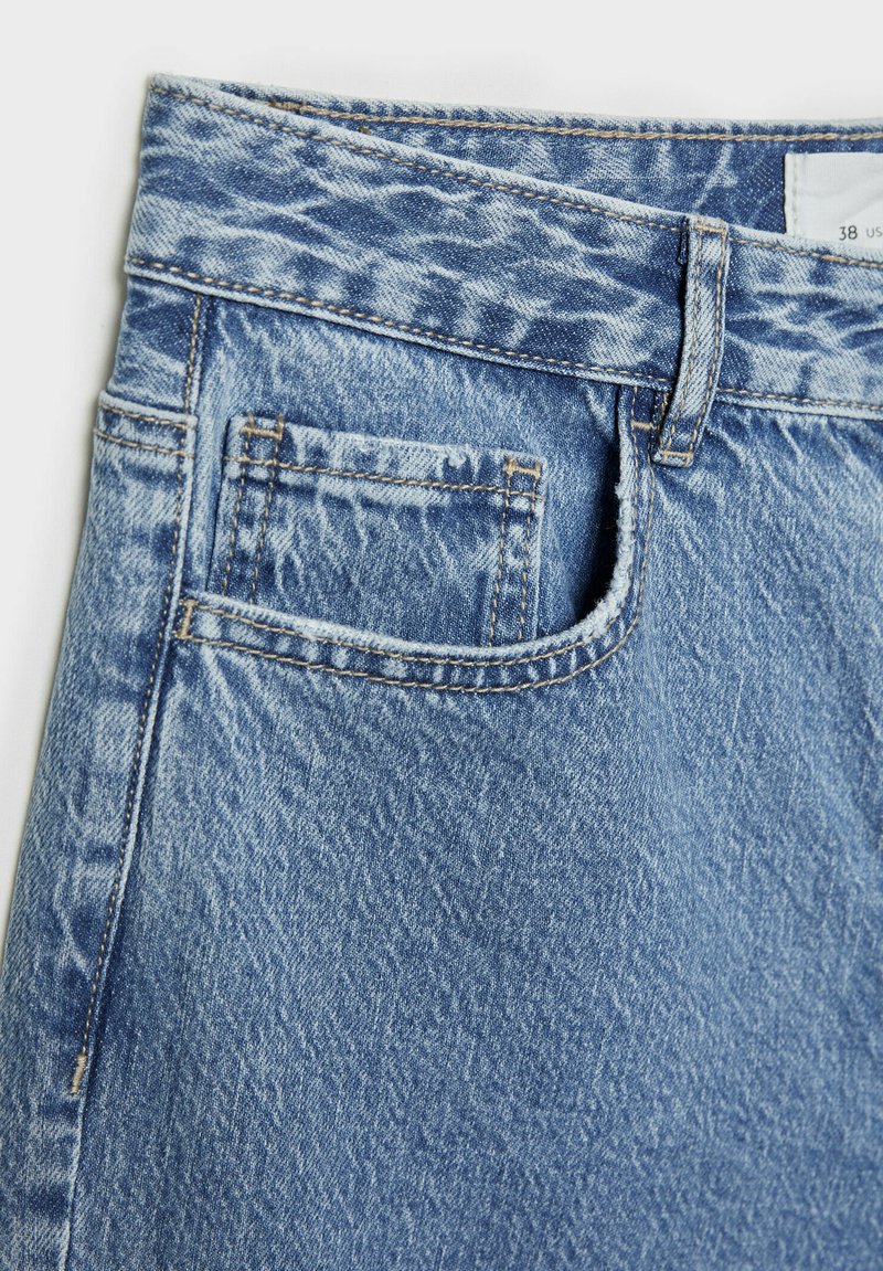 Hellblaue Jeans aus Denim mit einem standardmäßigen Bund, einer Fronttasche und subtiler, ausgebleichter Textur mit genähten Details.