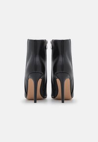 Stivaletti neri in pelle con tacco alto, dalla silhouette elegante, chiusura con cerniera e punta affusolata; texture liscia con finitura lucida.