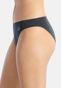 Sous-vêtements hipster en coton noir avec une texture lisse, un design taille basse et un logo discret sur la ceinture. Offre une couverture minimale.