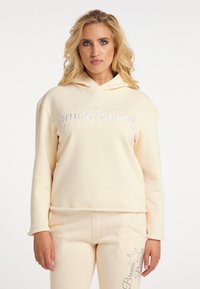 Lichtbeige hoodie met geborduurde tekst "bruno banani". Zachte stof, ontspannen pasvorm en geribbelde manchetten. Gecombineerd met bijpassende broek.