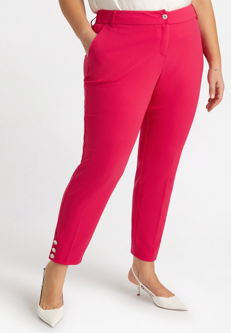 Pantaloni su misura rosa con una trama liscia, design affusolato e tre bottoni decorativi su ogni polsino. Abbinati a tacchi bianchi.