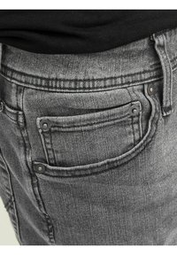 Graue Jeans aus Denim mit einer strukturierten Oberfläche, ausgestattet mit einem klassischen Design der Gesäßtaschen, Metallnieten und einem taillierten Bund.