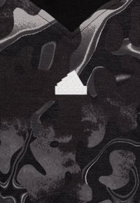 Camiseta Adidas negra y gris con cuello en V, que presenta un patrón texturizado, un logo texturizado prominente en el pecho y tela suave.