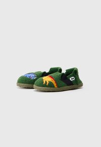 Chinelos verdes de feltro com painéis laterais elásticos, apresentando desenhos de dinossauros bordados em azul e laranja. Solas de borracha para aderência.