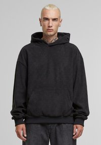 Sweat à capuche noir en tissu texturé avec un motif à carreaux. Comprend une poche frontale et des poignets et un ourlet en côte.