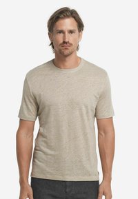 Beige t-shirt med kort ärm, mjuk textur och rundad halsringning, med subtilt spräckligt mönster och rak skärning.