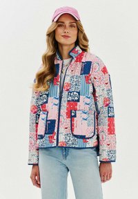 Barevná prošívaná bunda s kombinací květinových a geometrických vzorů v růžové, modré a červené barvě, s vysokým límcem a předními kapsami.