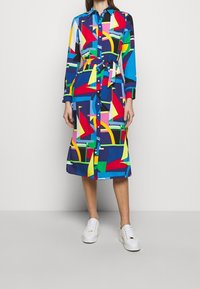Knapp-up skjortklänning med ett färgglatt geometriskt mönster i blått, rött, gult och grönt, med midjeband och långa ärmar.