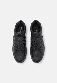 Svarta sneakers med en texturerad läderöverdel, syntetiska remmar med geometriskt mönster och en vadderad krage för komfort.