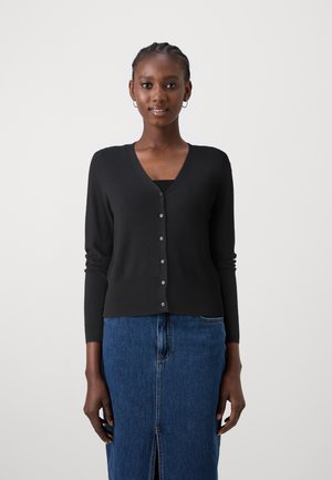 Zwarte cardigan met een V-hals, lange mouwen, knoopsluiting aan de voorkant en een zachte textuur, gecombineerd met een spijkerrok met een split aan de voorkant.