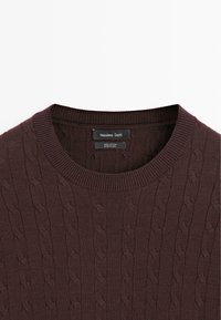 Brauner Baumwollpullover mit geripptem Rundhalsausschnitt und strukturiertem Zopfmuster. Das Etikett trägt die Aufschrift "Massimo Dutti."