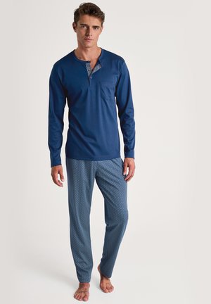 Navy blue long-sleeve pajama top with a patterned collar and pocket; paired with patterned blue pants featuring a geometric design.