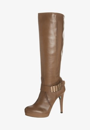 Bota de cuero marrón hasta la rodilla con tacón de plataforma, que presenta una correa ancha y detalle de hebilla metálica cerca del tobillo. Textura suave, diseño elegante.