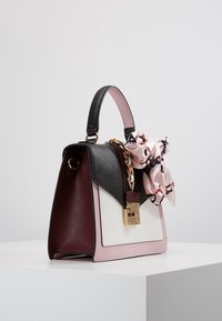 Strukturalna torebka z panelami w kolorach czarnym, bordowym, różowym i białym. Charakterystyczne złote okucia oraz różowy szalik jako akcent. Gładkie i teksturowane materiały.