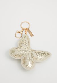 Portachiavi a forma di farfalla realizzato in pelle color crema con dettagli metallici dorati e ali intagliate; attaccato a un anello portachiavi in tono dorato.