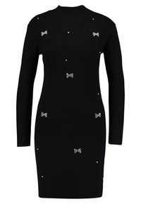 Robe en tricot côtelé noire à manches longues, col haut, ornée de détails en nœud argenté et de bijoux en gemmes. Silhouette ajustée, longueur genoux.