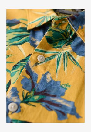 Kurzarmhemd aus gelbem Baumwollstoff mit blauem und grünem Blumenmuster. Verfügt über eine Knopfleiste und ein klassisches Kragen-design.