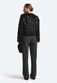 Must have mustriga mustri ja sequins, koos hallide sirgete pükstega. Hoidab vastava mustri musta sequins tõmblukuga kotti. Minimalistlik disain.
