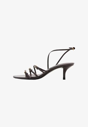 Sorte strop sandaler med tre slanke stropper, en tynd ankelstrop, spids tå og en 2,5 tommer stiletto hæl. Glat lædertekstur.