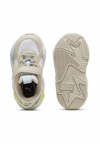 Scarpe da ginnastica beige con materiale in rete e sintetico, cinturino in Velcro, dettagli in azzurro chiaro e suole in gomma testurizzata. Presentano un tab in gomma circolare sul tallone.