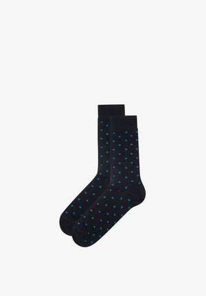 Calcetines negros hasta la mitad de la pantorrilla con pequeños lunares azules uniformemente distribuidos, colocados planos uno al lado del otro sobre un fondo blanco.