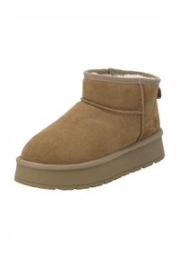 Bottine en suede tan avec un bout rond, un bord de col, et une semelle en caoutchouc texturée. Présente une bande décorative cousue et une languette à l'arrière.