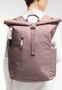 Zaino a roll-top in morbido tessuto mauve, con una tasca esterna con zip, tasche laterali e una cinghia centrale con chiusura a fibbia.