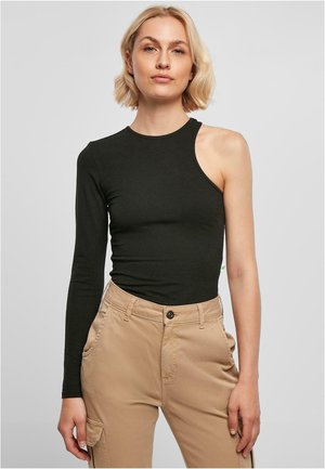 Svarte langermede topp med en skulderutskjæring, laget av elastisk materiale. Fitted design med rund halslinning. Kombinert med beige bukser.