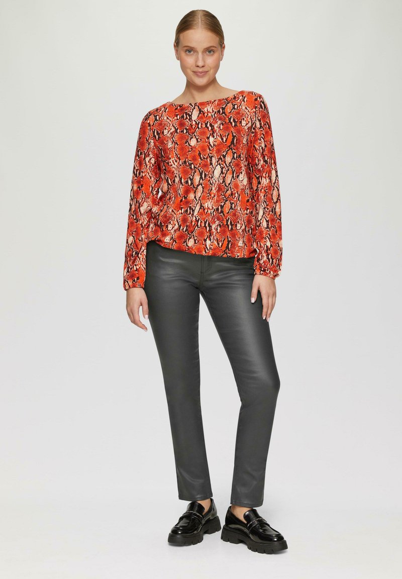 Rood en zwart slangenprint langlijf top, gecombineerd met glanzende zwarte slim-fit broek en dikke zwarte schoenen. Eenvoudig, modern ontwerp, zonder zichtbare patronen.